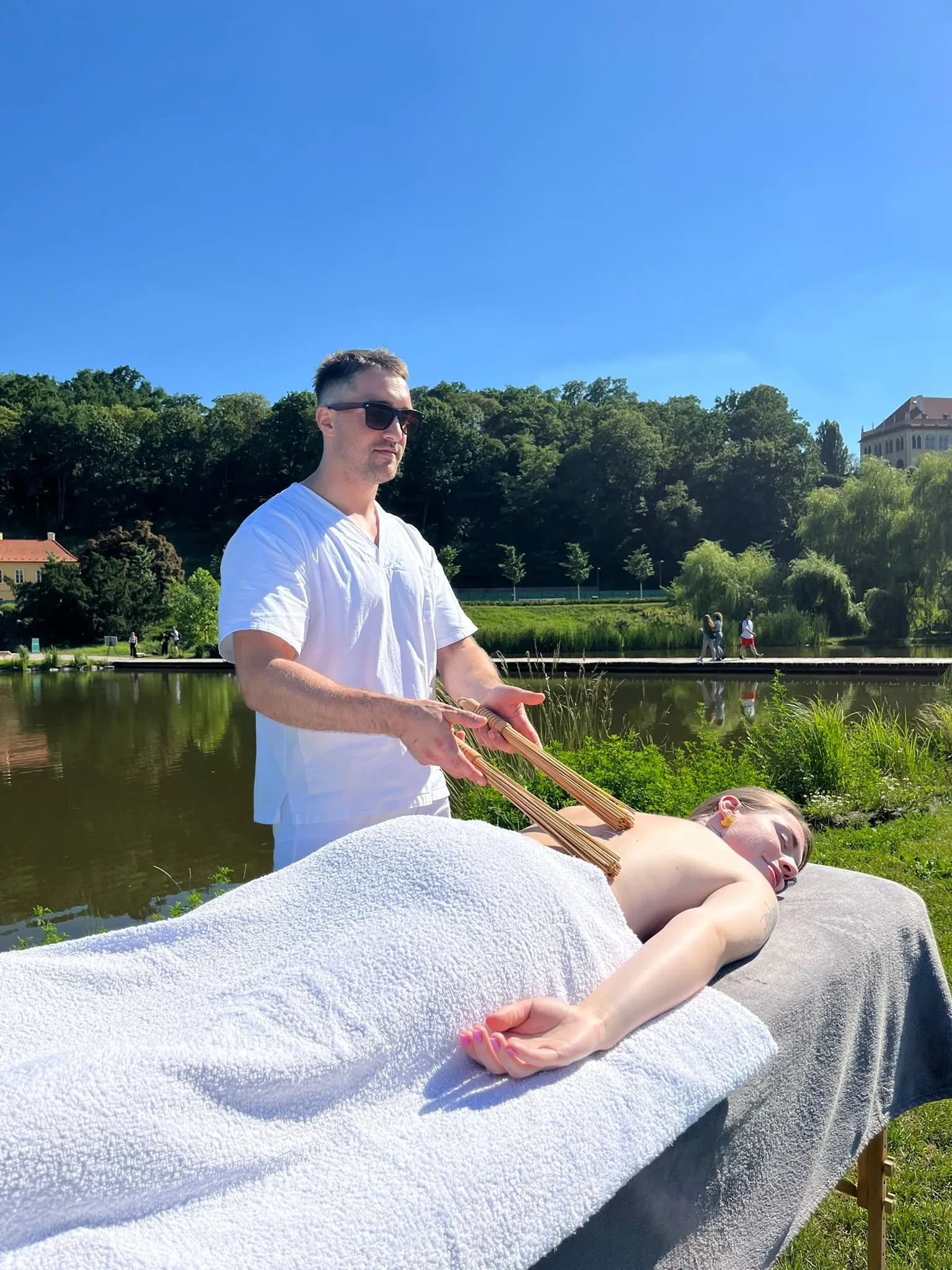 A bamboo stick massage by a lake, seen from the side