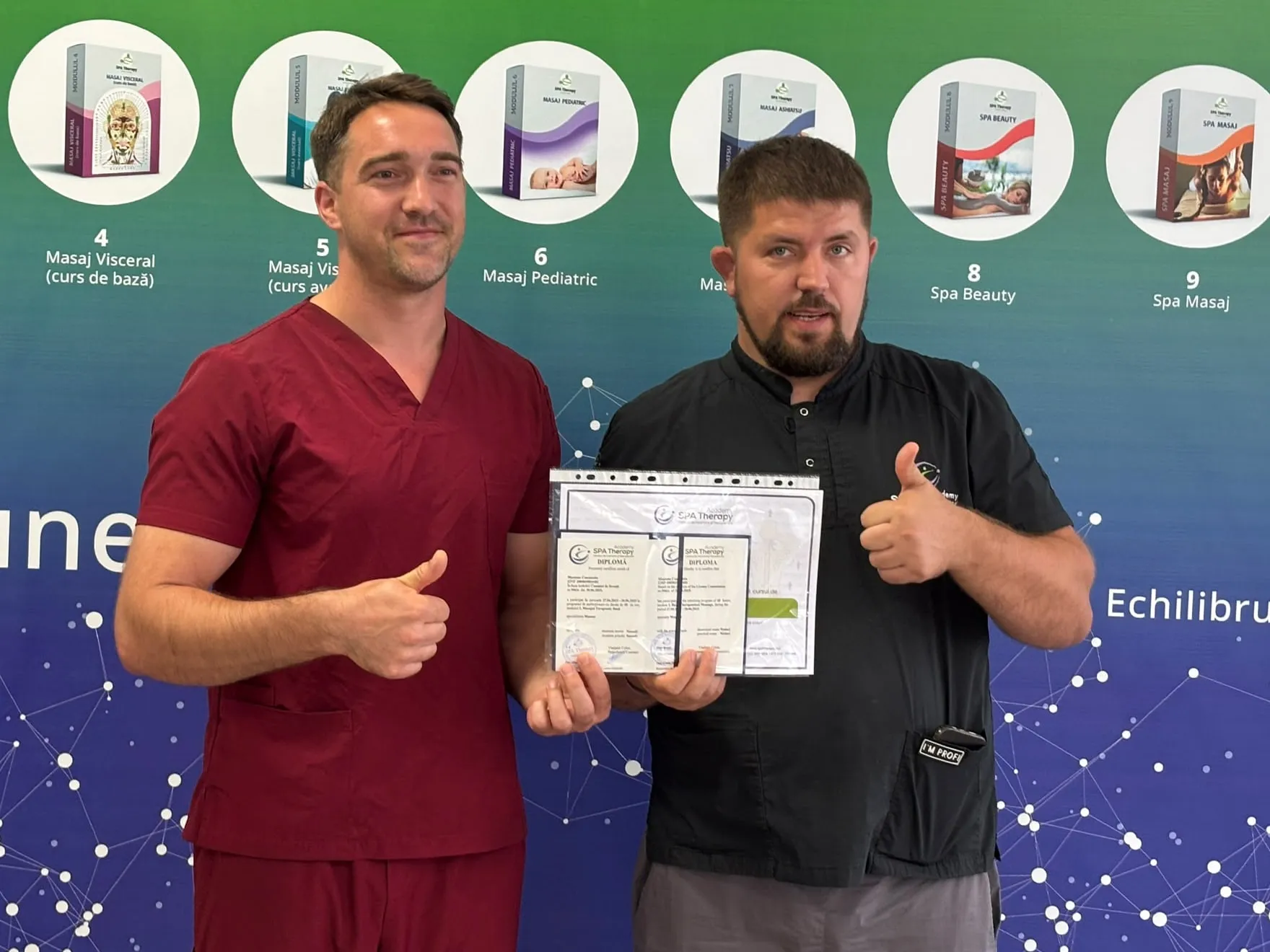 Constantin in burgundy work scrubs holding his massage diploma, next to his trainer at a training centre