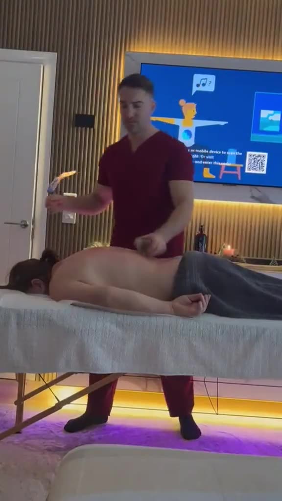 A therapist preparing cupping glasses beside a client lying face down