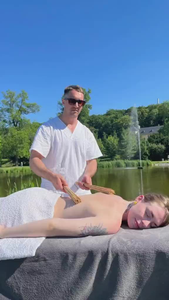 A back massage by a lake, from a wide view to a close-up of the hands